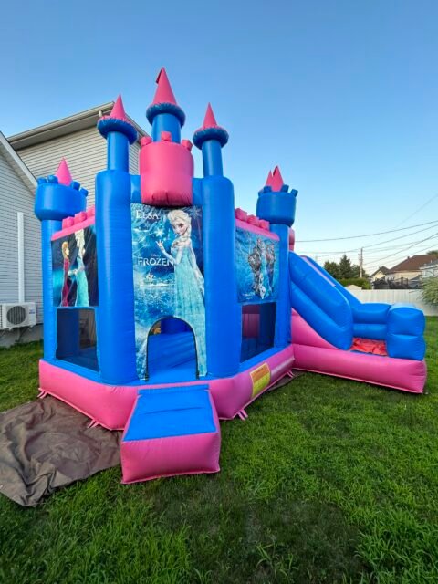 Ch&acirc;teau gonflable Reine des Neiges rose et bleu, tourelles et glissade lat&eacute;rale, install&eacute; sur une pelouse