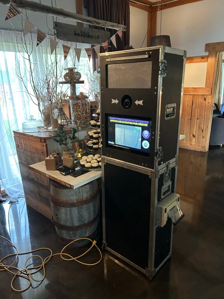 Borne photo &Eacute;venox install&eacute;e devant un d&eacute;cor de mariage champ&ecirc;tre : tonneau de bois, table de desserts et fanions
