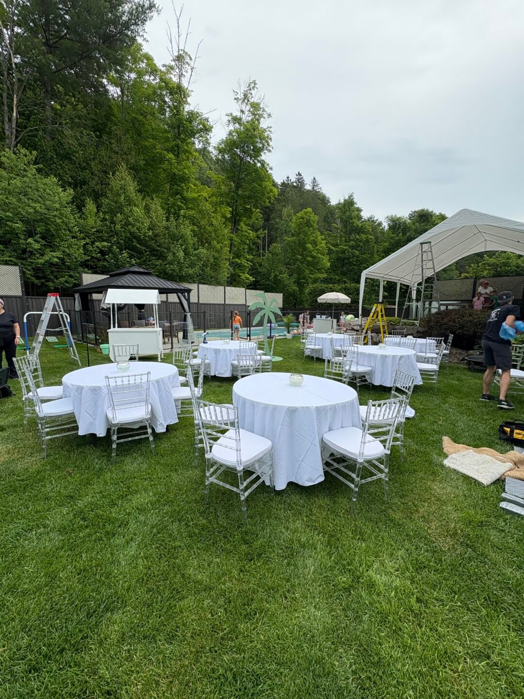 Montage Evenox en cours sur un terrain : tables rondes nappées, chaises Chiavari, chapiteau et échelles
