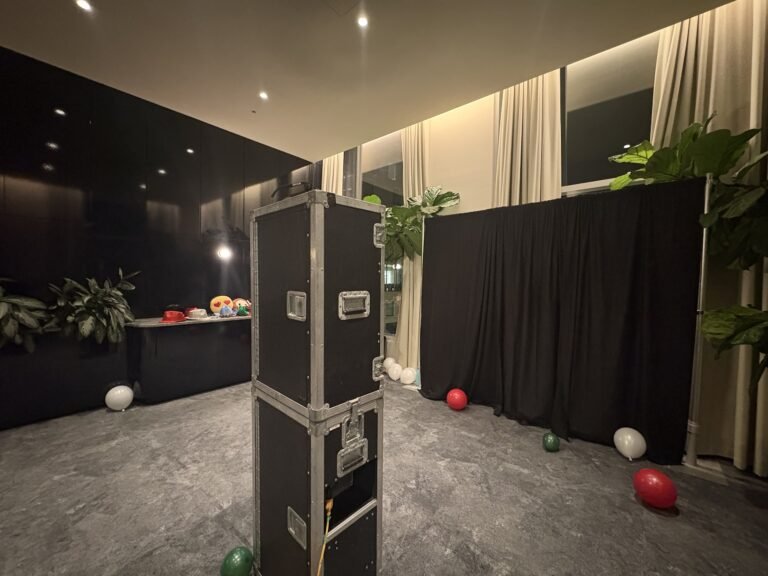 Borne photo &Eacute;venox dans une salle d&eacute;cor&eacute;e de rideaux noirs, plantes et ballons rouges, blancs et verts au sol