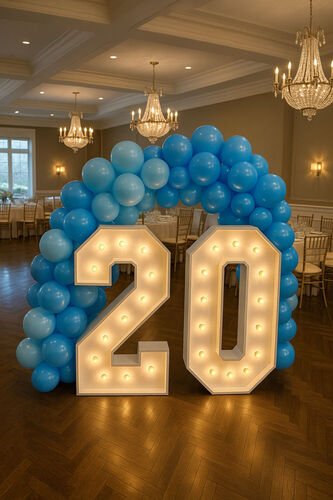 Chiffres lumineux géants formant 20 sous une arche de ballons bleus, dans une salle à lustres