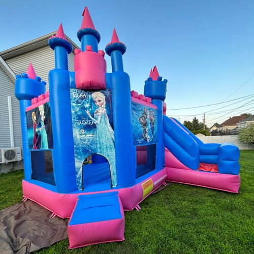 Château gonflable Reine des Neiges XL, bleu et rose, avec ses tourelles et sa glissade, monté sur une pelouse