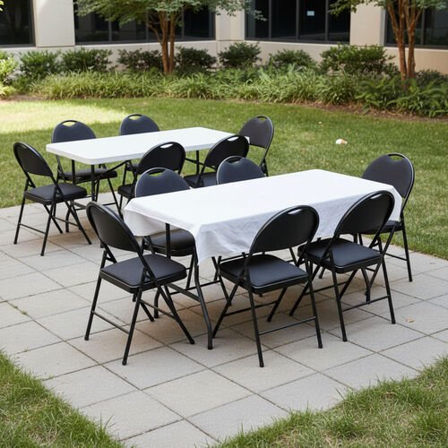 Deux tables pliantes rectangulaires, l'une nappee de blanc, entourees de chaises pliantes noires, dressees sur une terrasse de pave