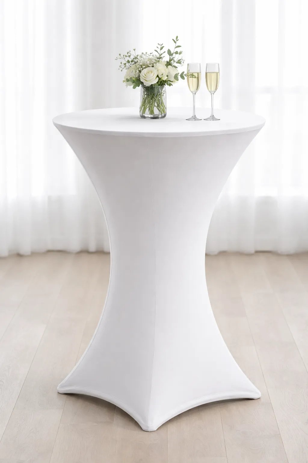 Nappe extensible blanche sur une table à cocktail, avec un bouquet et deux flûtes posés dessus