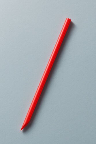 Paille jumbo rouge à bout biseauté, posée en diagonale sur un fond gris