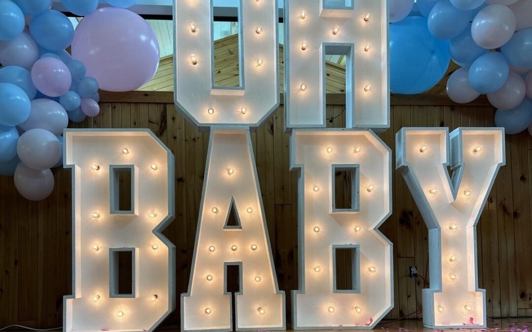 Lettres lumineuses OH BABY d'Évenox allumées, confettis roses au sol après la fête