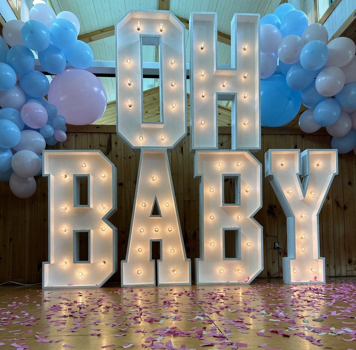 Lettres lumineuses OH BABY d'Évenox allumées, confettis roses au sol après la fête