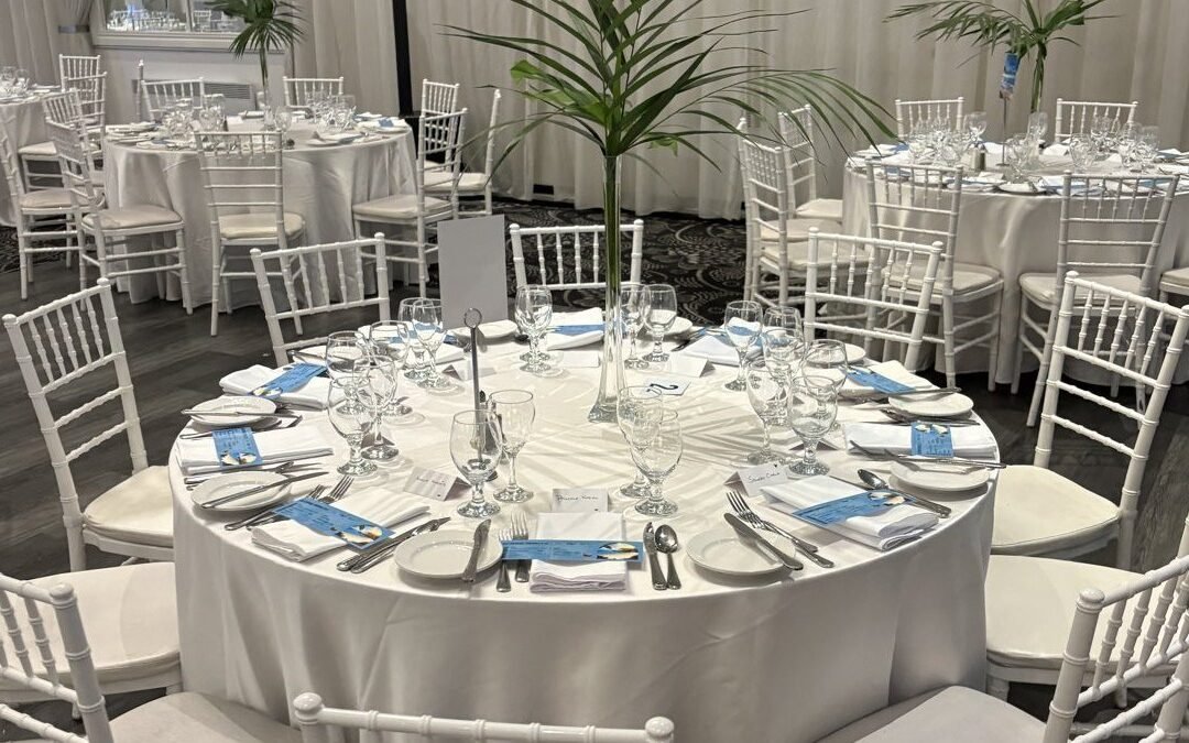 Salle de réception dressée avec tables rondes nappées de blanc et chaises Chiavari blanches Évenox